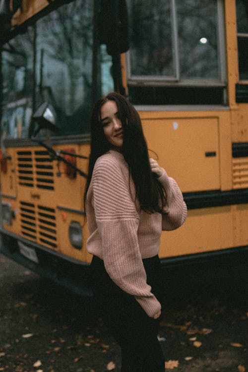 Woman Wearing a Sweater Standing Beside Yellow Bus