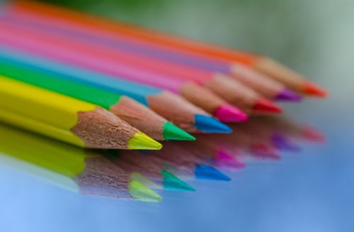 Free Close-up of colorful pencils reflecting on a glass surface, showcasing creativity and art. Stock Photo