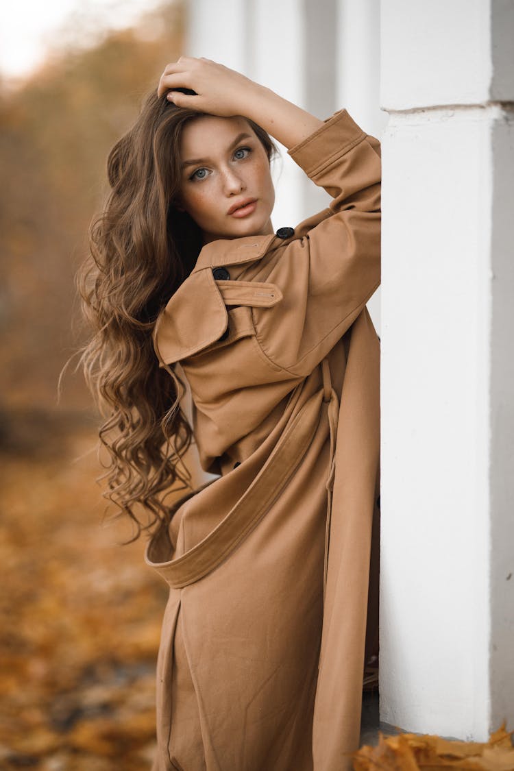 Attractive Woman Leaning Against Wall Of Building In Autumn Scenery