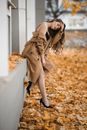 Woman in Coat ans Stilettos Leaning against Building and Uncovering Her Shoulder