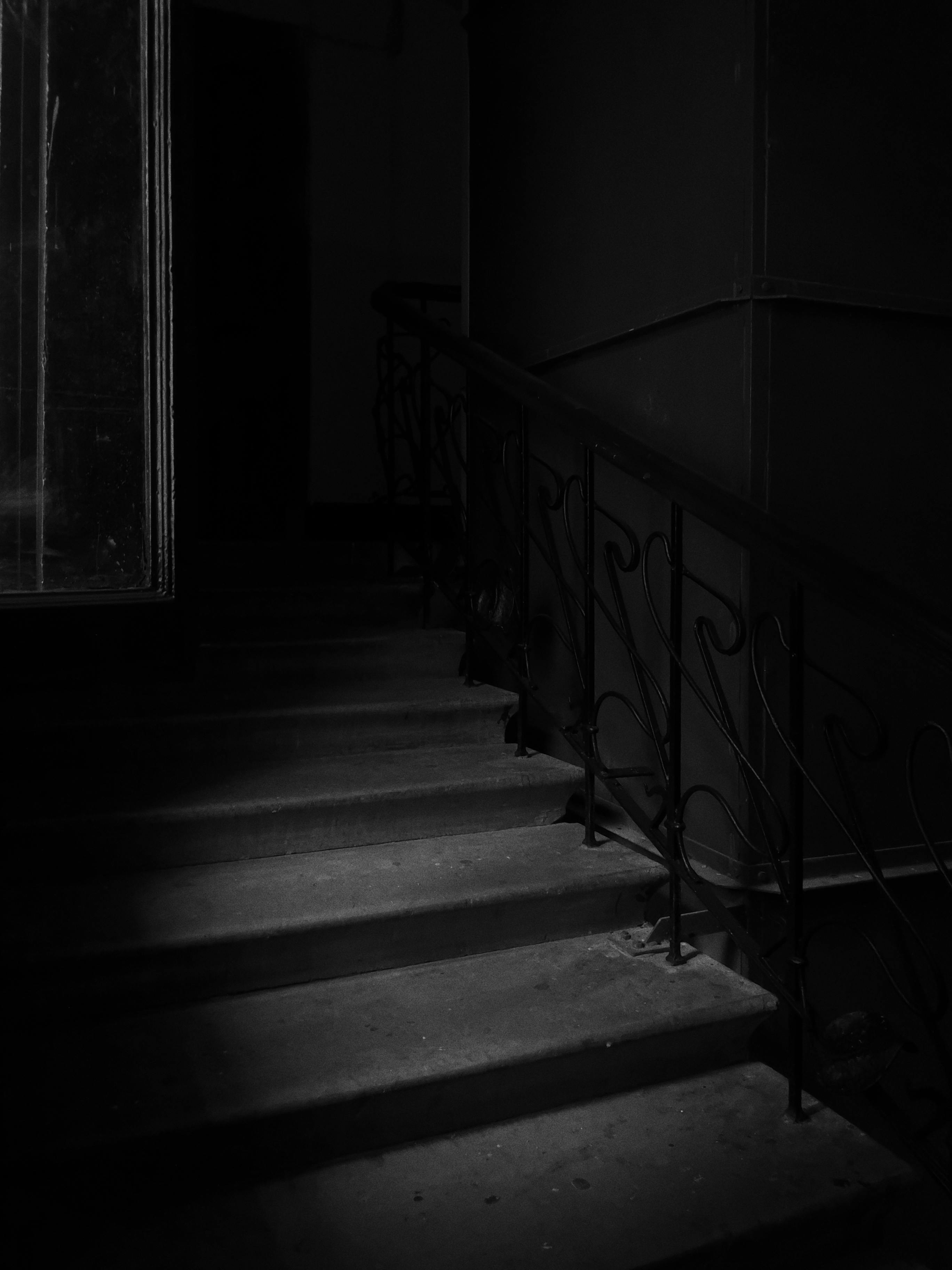 Monochrome image of an eerie staircase casting shadows, adding a dramatic tone.