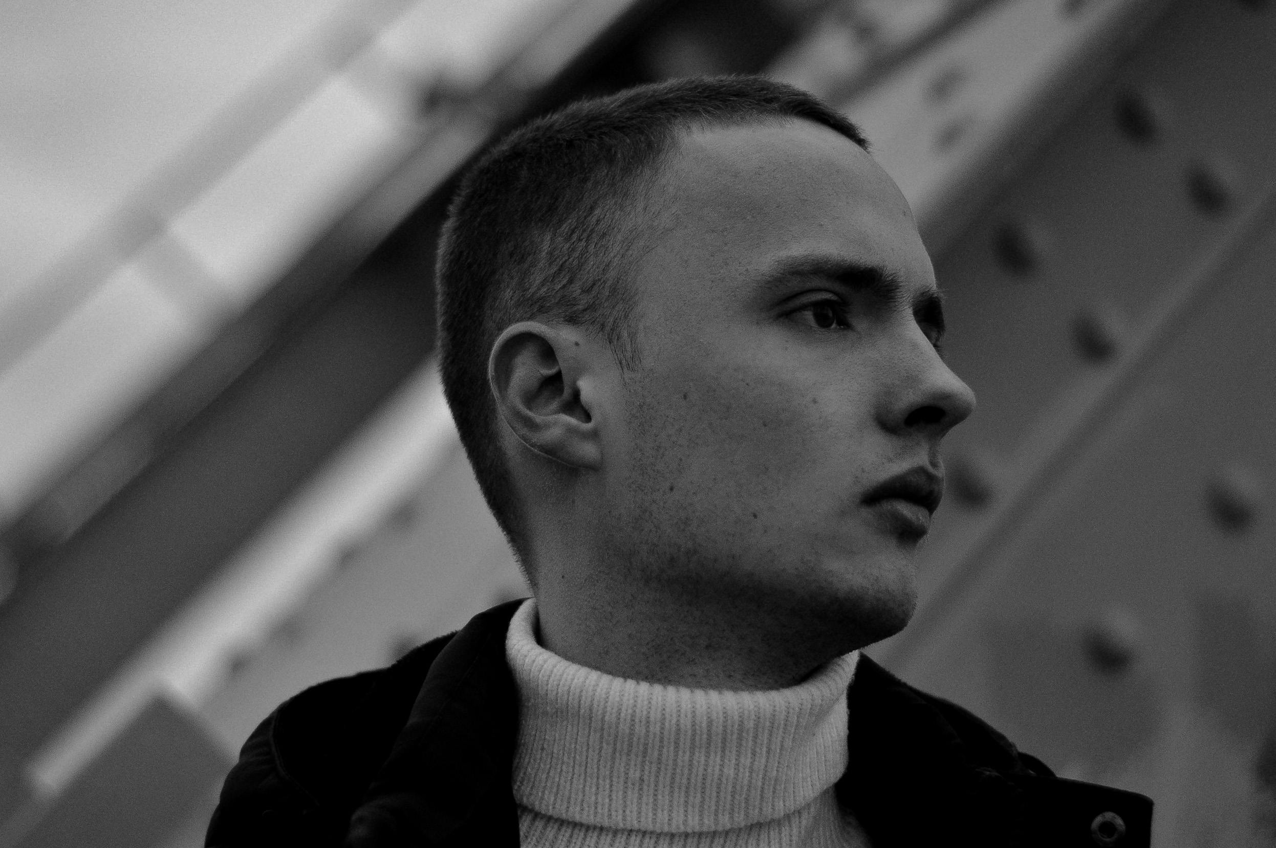 Black and white profile portrait of a man in a turtleneck sweater with a thoughtful expression.