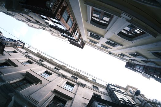 A dramatic low-angle shot showcasing historic urban architecture against a bright sky.