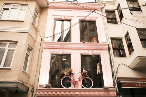 Free Low-angle shot of a pink building facade featuring a decorative bicycle. Urban charm and creativity. Stock Photo