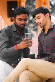 Two men in conversation, using a smartphone outdoors. Casual and modern communication scene.