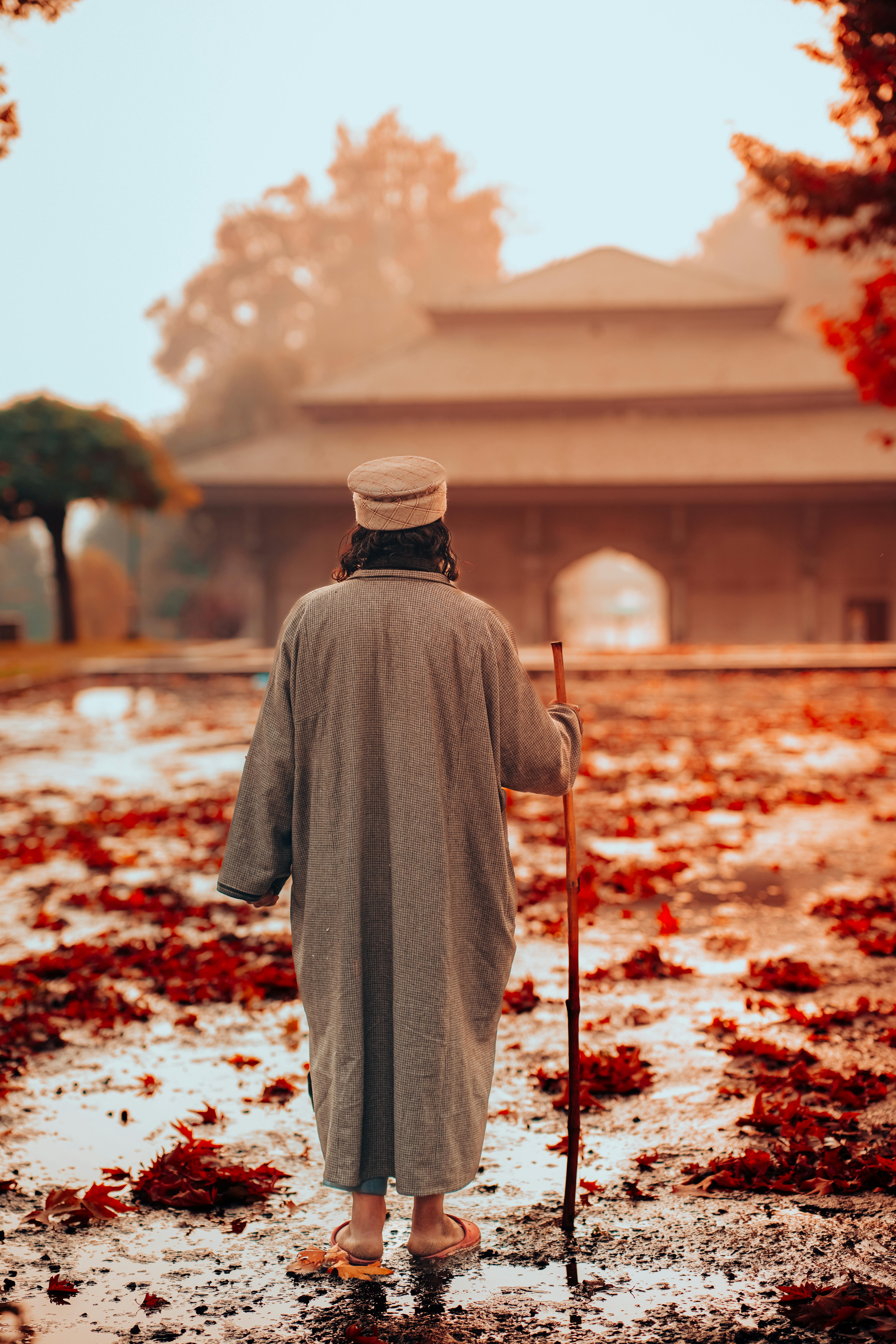 Person in traditional attire walking in autumn, Srinagar, Kashmir.