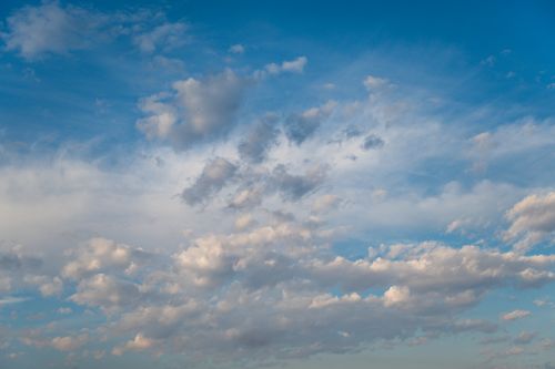 Free Soft white clouds scattered against a bright blue sky, creating a serene and peaceful atmosphere. Stock Photo
