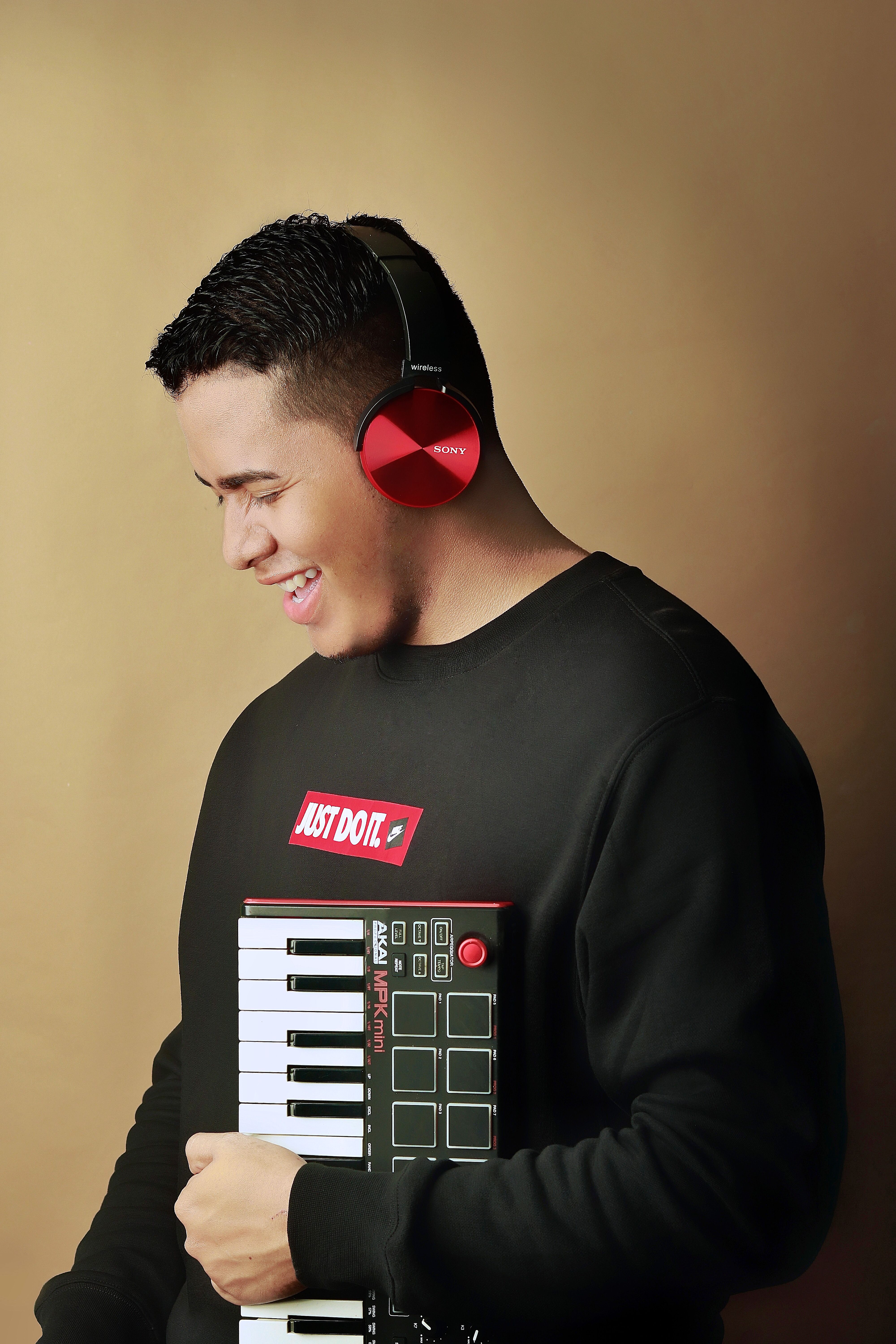 Cheerful man in headphones holding a keyboard, enjoying music indoors.