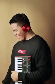 Cheerful man in headphones holding a keyboard, enjoying music indoors.