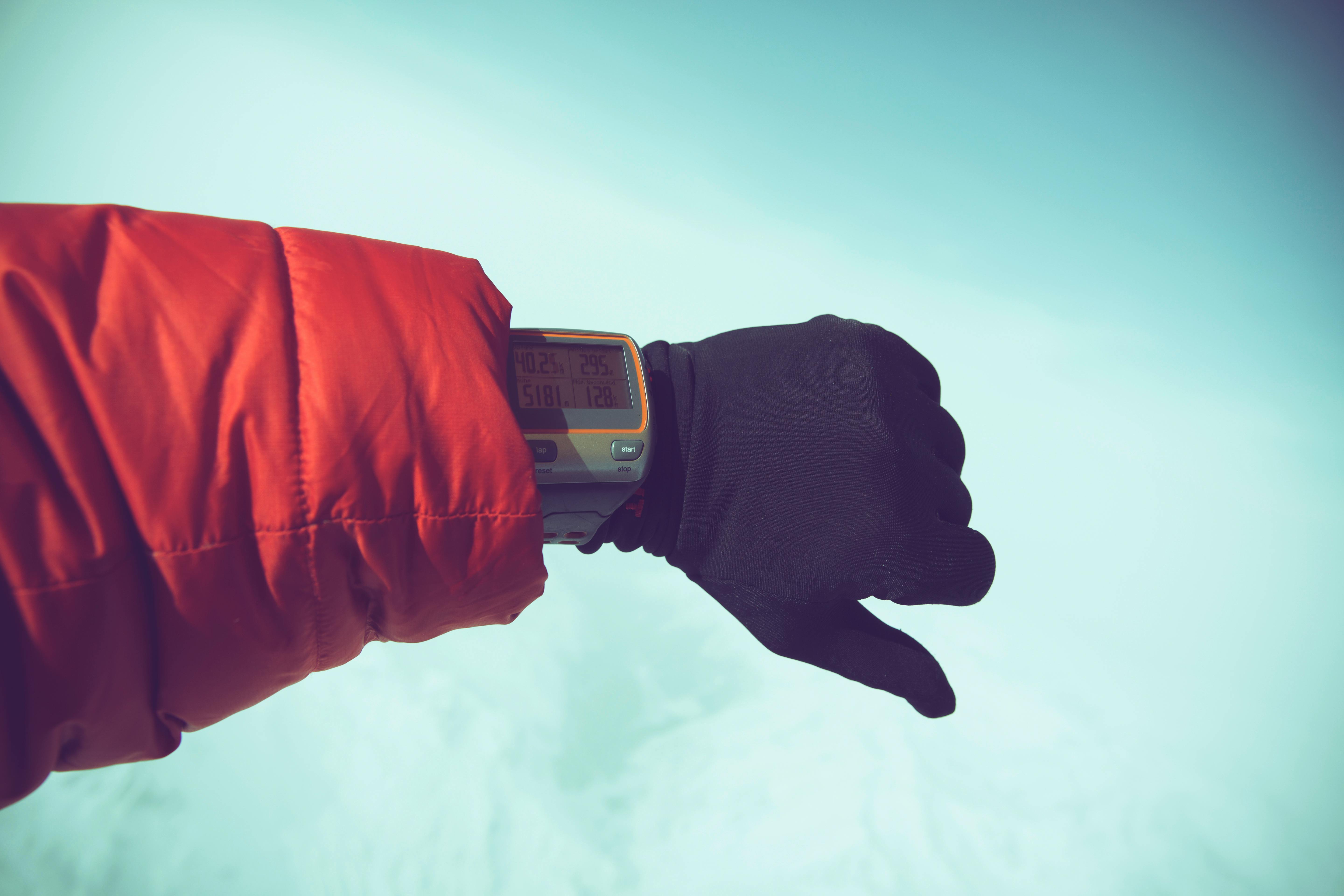 一只戴着手套的手腕上戴着户外数字手表，背景是白雪皑皑，暗示着冬季冒险