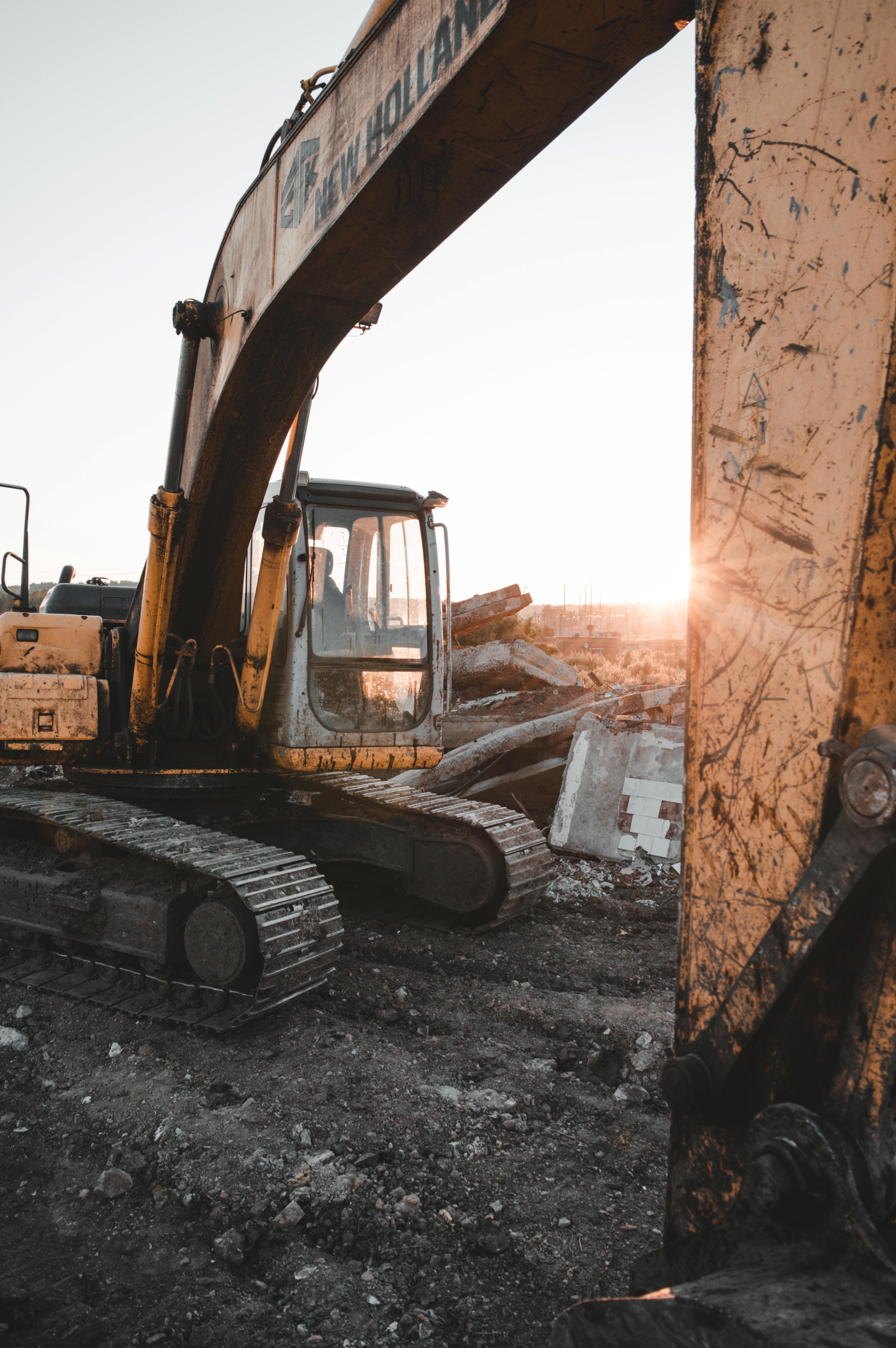 This Is A Yellow Excavator Being Used In Front Of A City With Skyscrapers  Powerpoint Background For Free Download - Slidesdocs