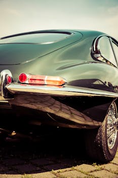 在阳光明媚的户外环境中，设计优雅的复古老爷车展示着闪亮的尾灯