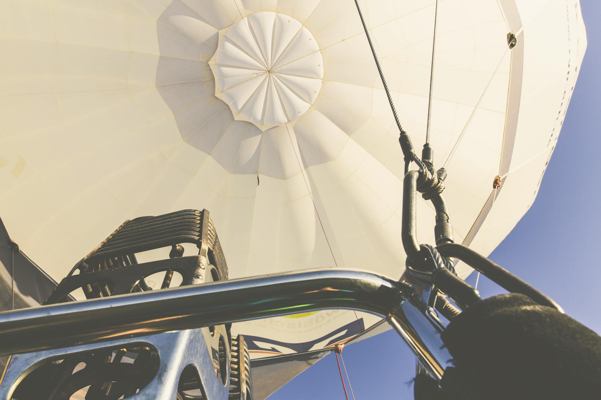 Detailed view of hot air balloon equipment mid-flight against clear blue sky.