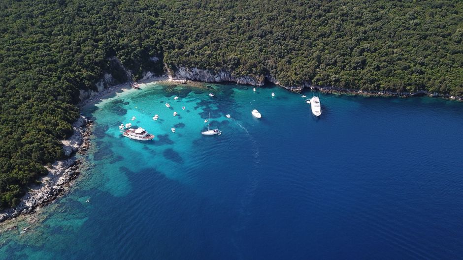 Breathtaking Kissamos Balos Lagoon Sunset Catamaran Cruise Review: Sailing Crete's Most Stunning Lagoon at Golden Hour Review 2026 - Aerial shot of a beautiful blue bay with boats and lush green forest in Thesprotia, Greece.