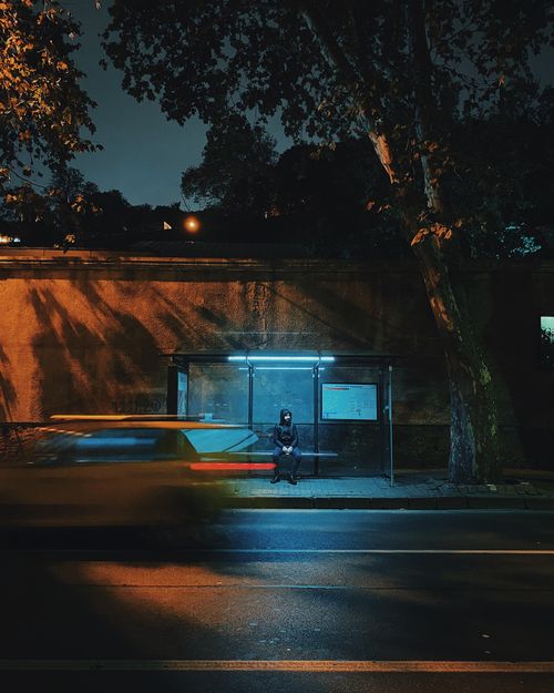 Free A solitary figure waits at a dimly lit Istanbul bus stop, captured with motion blur at night. Stock Photo