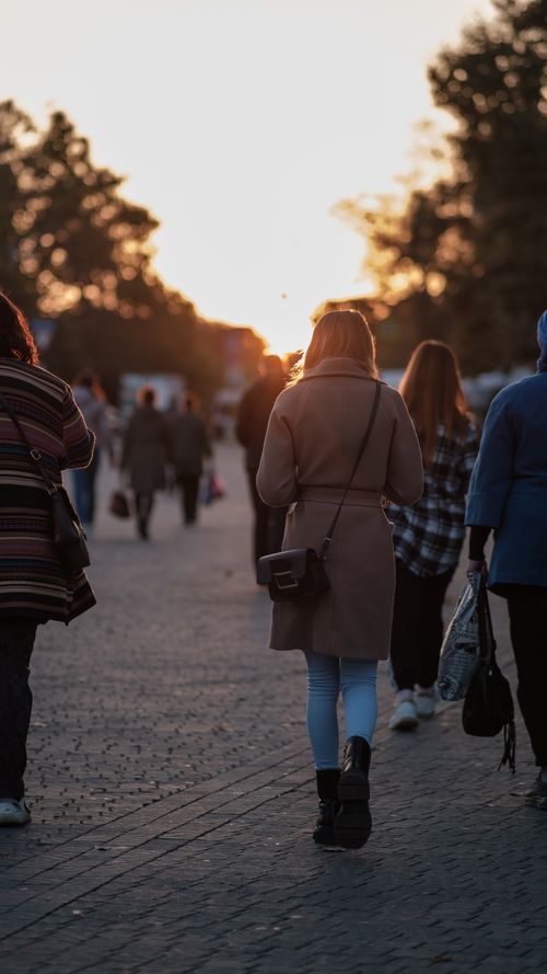 Free People walking along a busy street during sunset, creating a warm and lively atmosphere. Stock Photo
