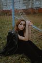 Woman in Black Dress Sitting on White Metal Fence