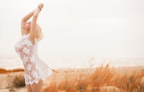 白天，一位穿着白色连衣裙的女人在海滩上感到自由自在