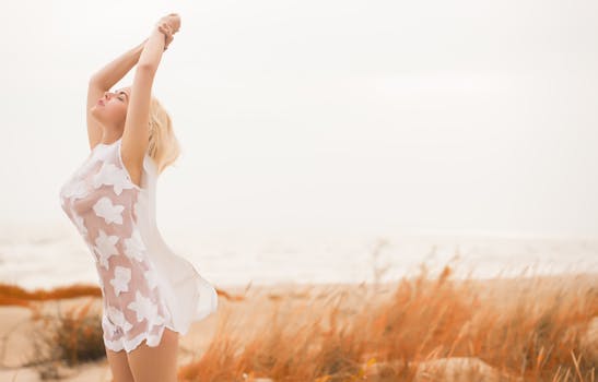 白天，一位穿着白色连衣裙的女人在海滩上感到自由自在