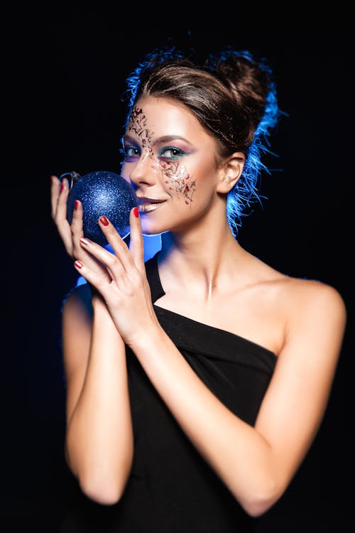 Woman Wearing Black One Shoulder Top Holding Bauble