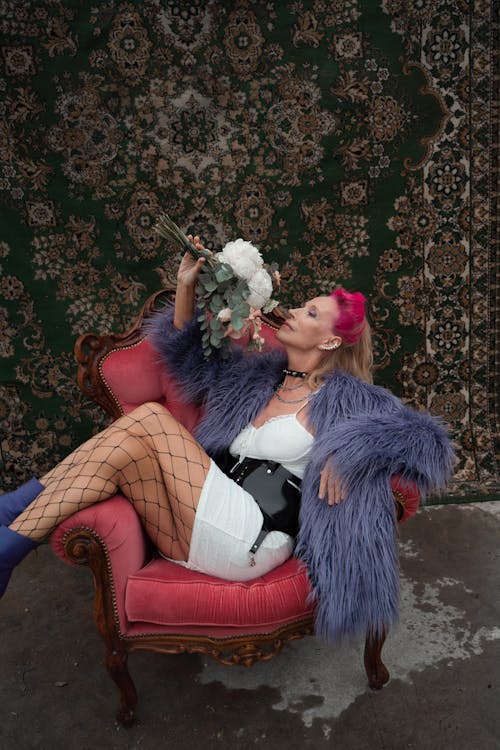 Woman with Pink Hair Sitting in an Armchair on the Background of a Rug
