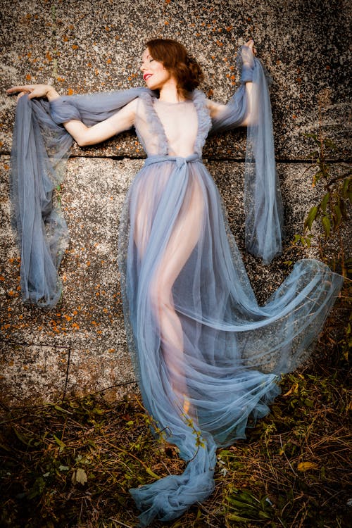 Kobieta Ubrana W Siatkową Niebieską Sukienkę Leżącą Na Szarej Betonowej Podłodze