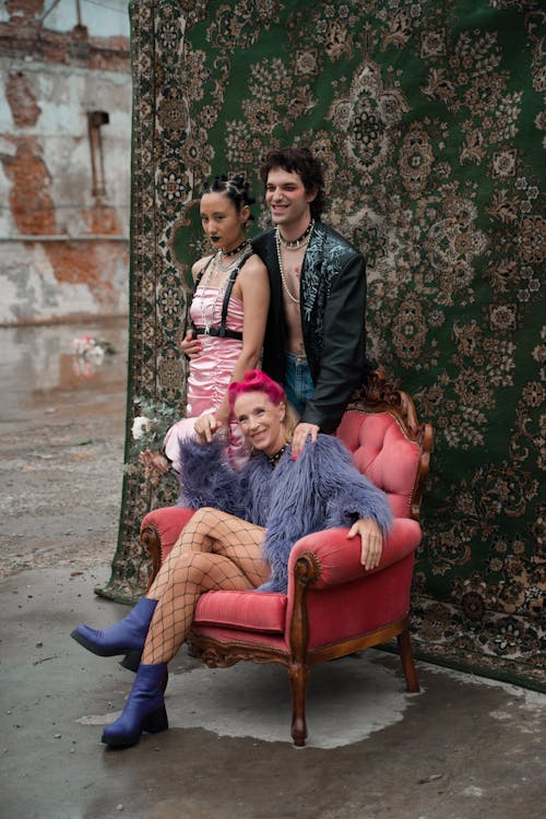 Group of People in Punk Costumes Posing against a Patterned Rug Hanging Outside 