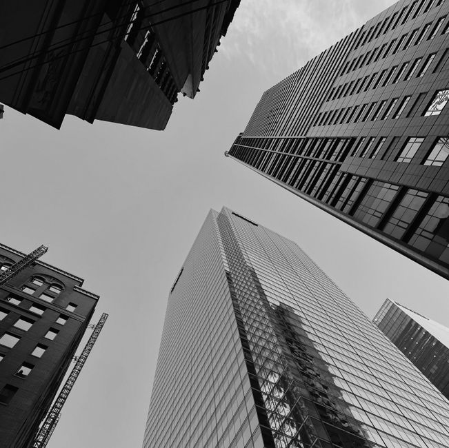 Low angle view of towering skyscrapers in a monochrome cityscape blending modern and classic architecture.