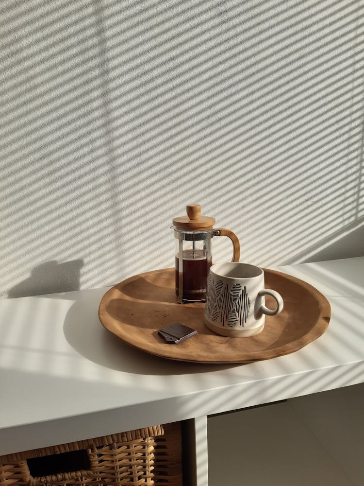 Coffee Brewer Mug And Piece Of Chocolate On Ceramic Plate On White Cupboard