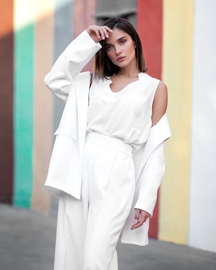 Woman Wearing White Clothes Posing In Front Of Colorful Wall