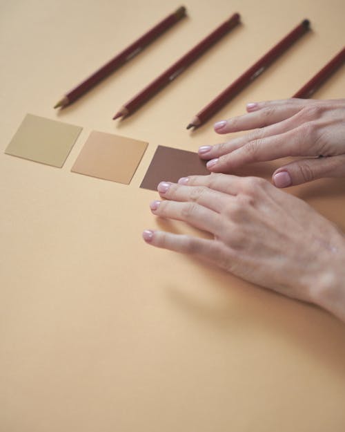 Free A Person Touching Brown Square Paper on Yellow Surface Stock Photo