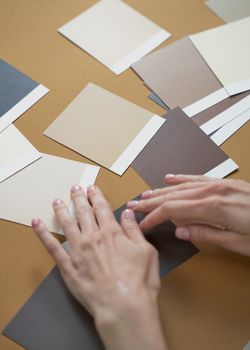 Close-up of hands delicately arranging neutral color swatches on a wooden table, highlighting design choice.. pexels, close,