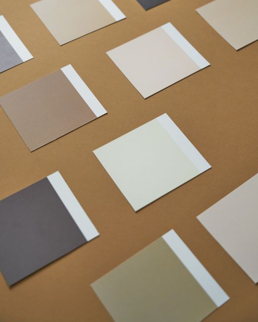 Collection of neutral color swatches on a brown paper background, arranged orderly.
