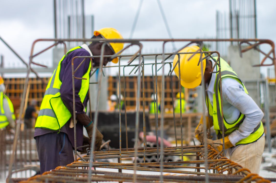 Free Men Working on a Construction Site while Wearing Hard Hats Stock Photo