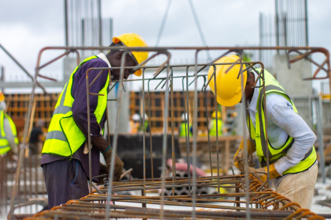grátis Trabalhadores da construção com capacetes e coletes de segurança trabalhando no local. Foto profissional