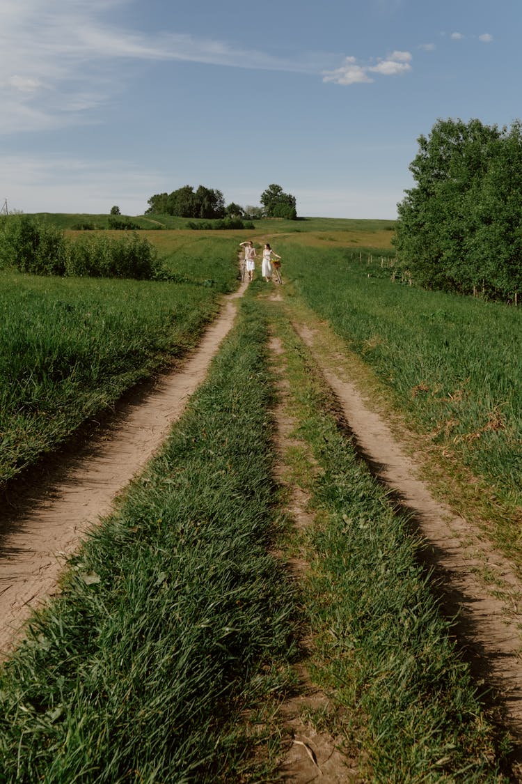 A Couple Walking Together On A Trail On A Grass Field