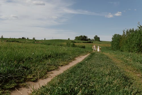 Woman and Man on Ground Road among Fields