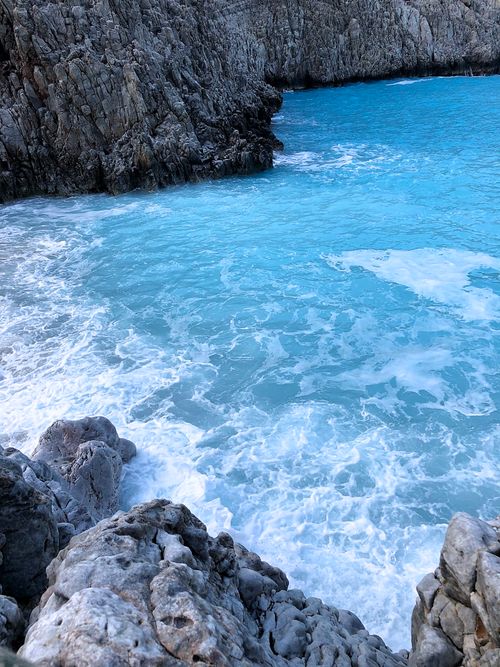 Free Explore a tranquil turquoise cove surrounded by rugged rocks and gentle waves. Stock Photo