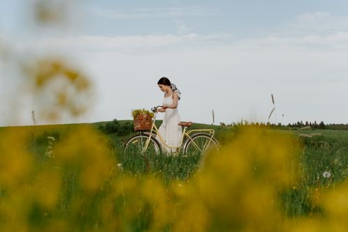 Free A woman in a field with a bicycle and flowers, enjoying a warm summer day. Stock Photo