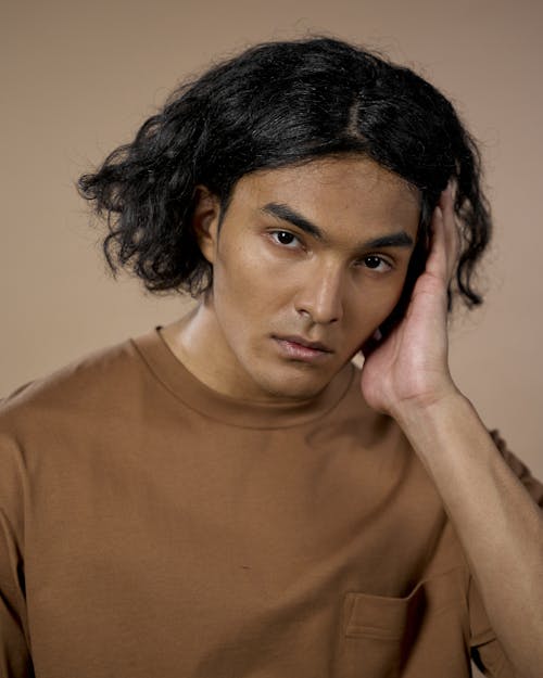 Foto profissional grátis de cabelo comprido, cabelo escuro, fundo marrom