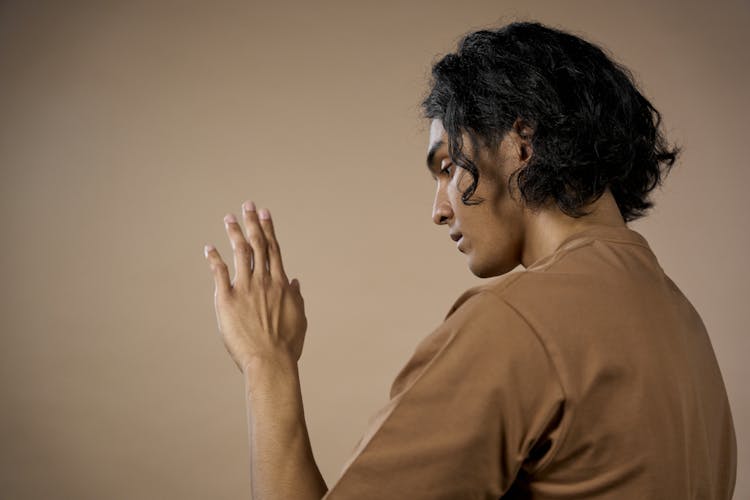 A Man In Brown Shirt Looking At His Hand