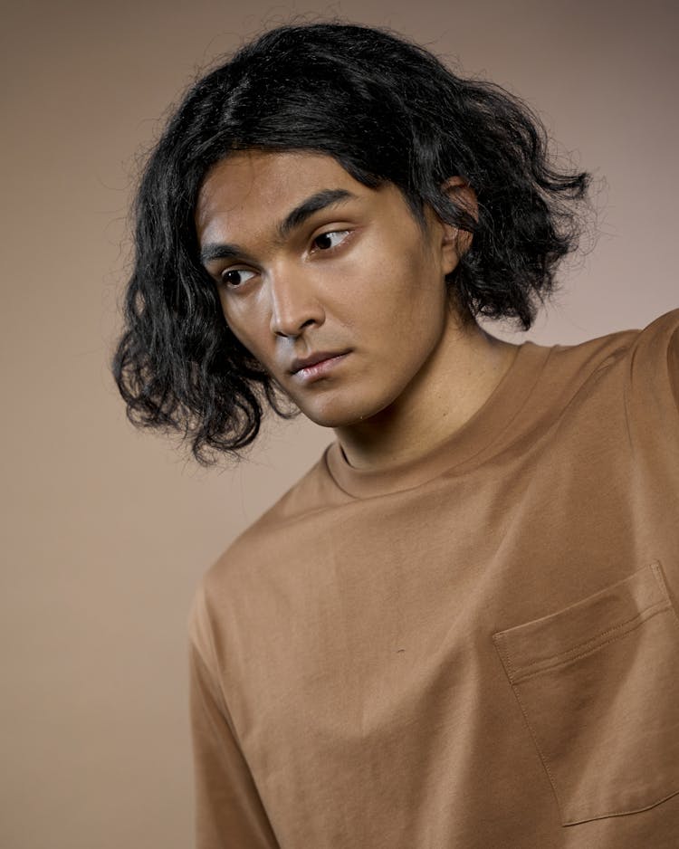 A Man In Brown Crew Neck Shirt With Wavy Hair