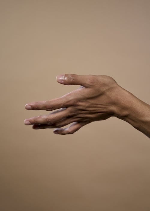 Person's Left Hand on Beige Background