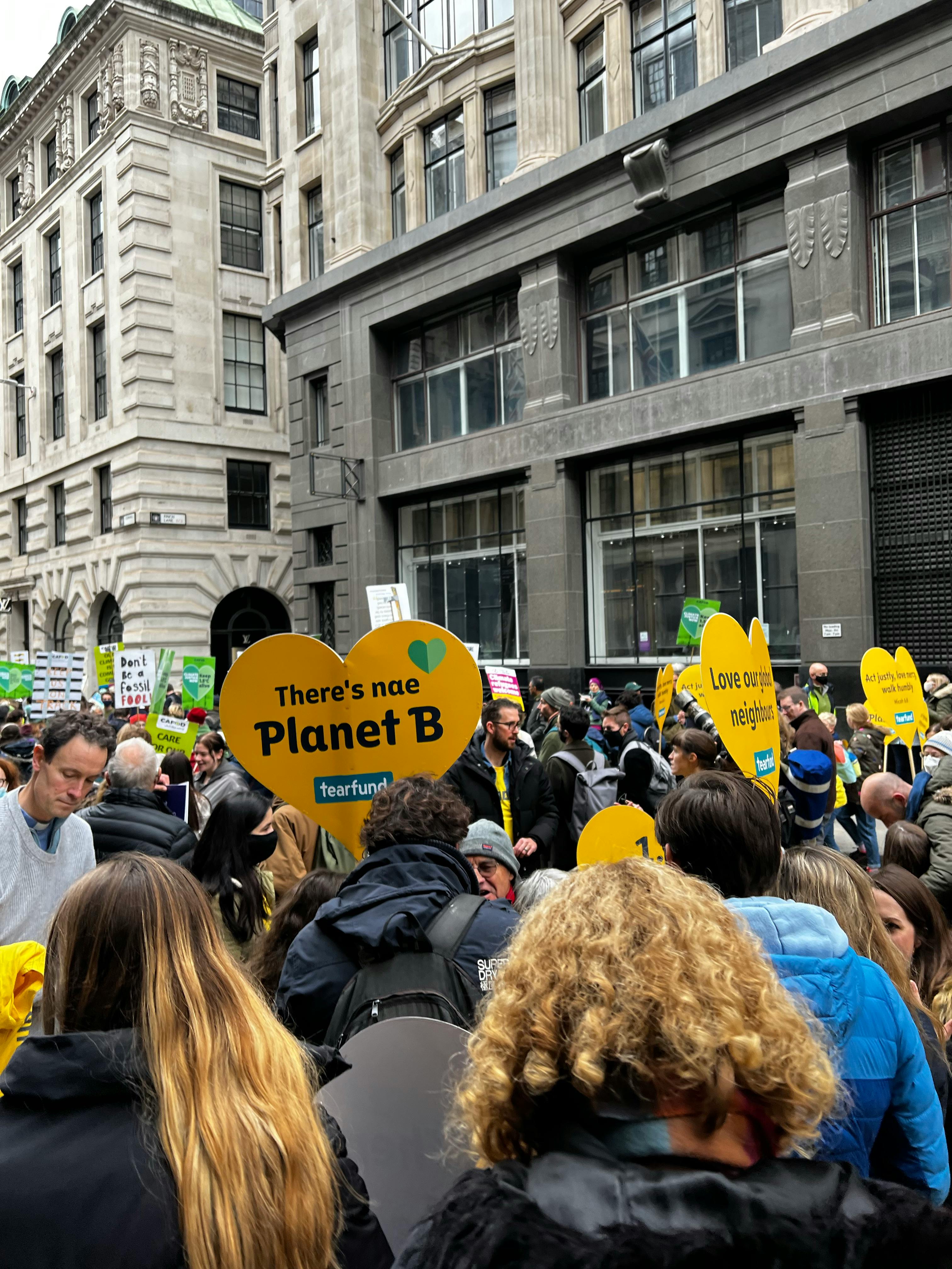 a gathering of people with yellow heart shaped placards