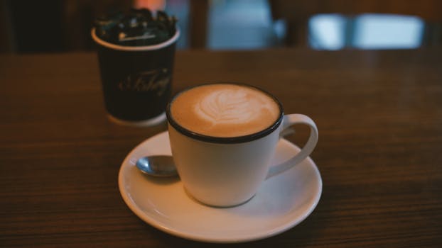 A beautifully crafted cup of coffee with latte art served on a wooden table in a cozy setting.