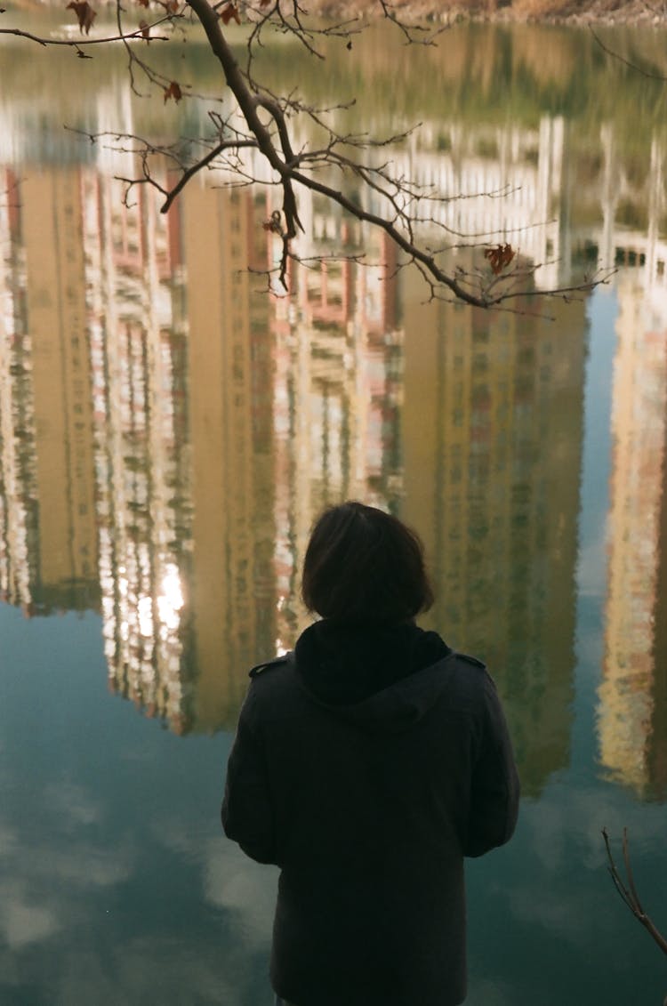 Back View Of A Woman And A Reflection Of City In The Lake