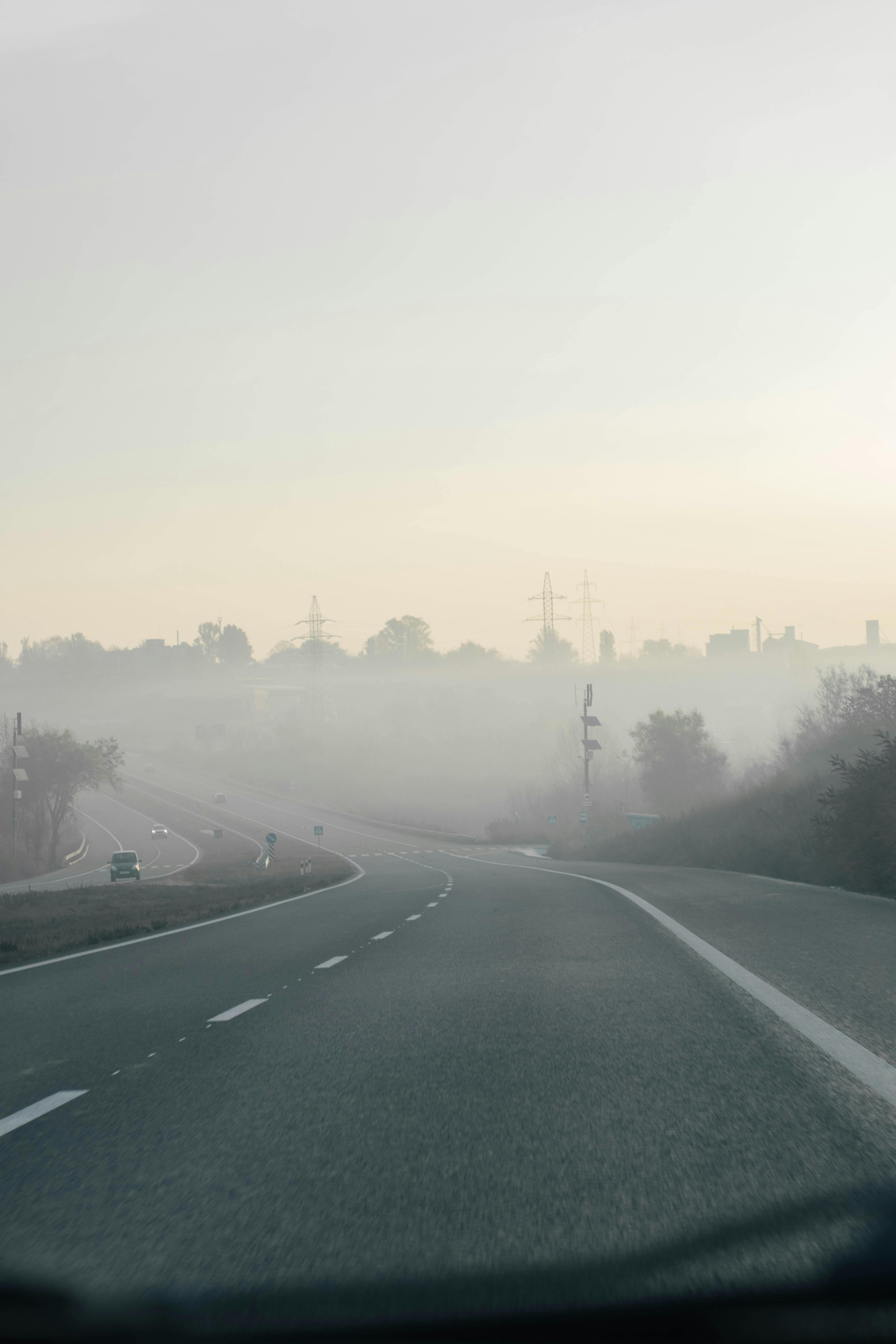 A serene drive along a foggy highway with misty trees and an open road, creating a calming atmosphere.