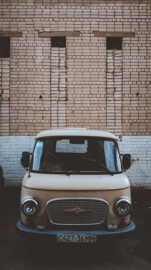 Free Front view of a vintage van parked against a rustic brick wall, showcasing retro design. Stock Photo