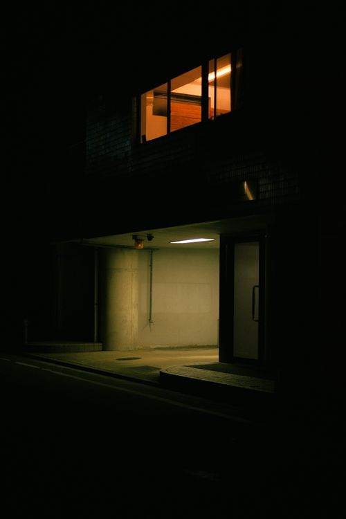 Free Nighttime scene of a building entrance with warm lighting and architectural features. Stock Photo