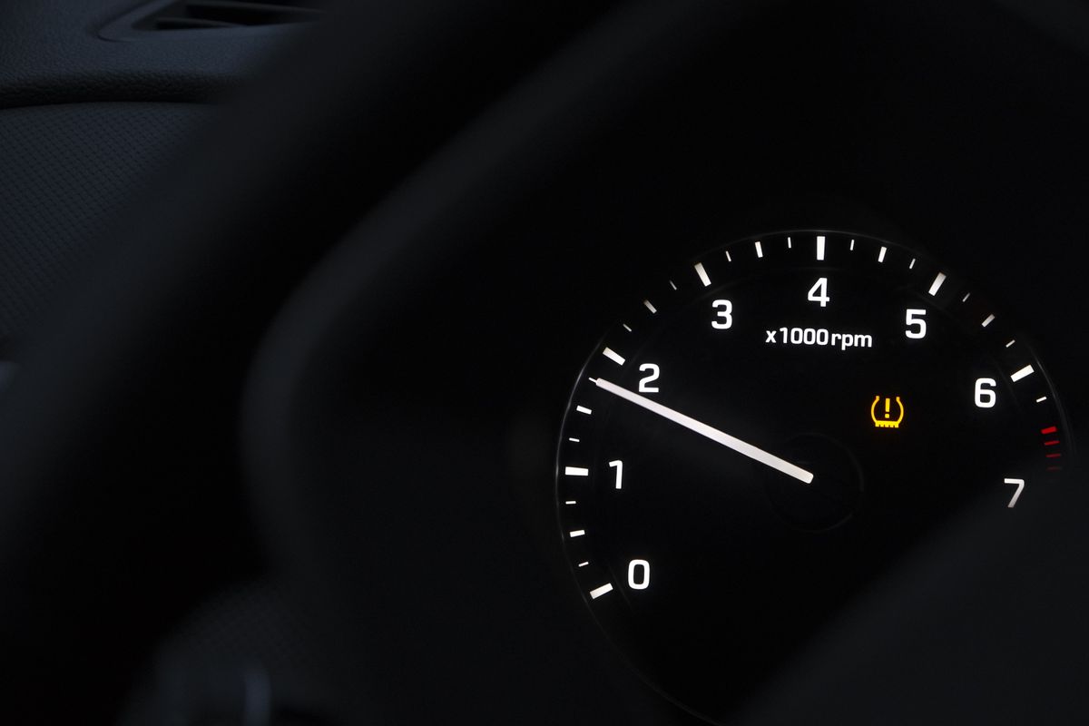 A detailed view of a car tachometer showing RPM alongside an illuminated tire pressure warning indicator